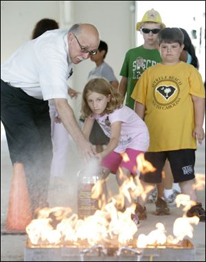 Larry Cser, assistant director of public safety/work place safety and health at Owens, shows Rebecca Cornell, 8, of Oregon how to use a fire extinguisher.