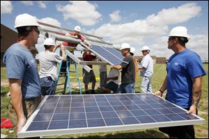 Parry Rentz, left, of Whitehouse and Mike Humphries of Shoup Solar Solutions carry a solar panel to the installers at a new solar array on the Owens Community College's Findlay campus.