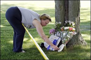 Kimberly Jones, Bryan Jones' mother, places flowes and a plaque at a memorial for her son.