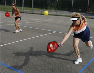 Judy Bastian, front, of Sylvania pairs with Paige Armstrong of Rossford for a game of Pickleball at the Glenwood Courts on Glenwood Road. The game is played with hard, solid-faced paddles and perforated plastic balls.