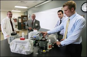 During a building tour, Dr. Curtis Black, clinical pharmacy professor, left, Mike Kitz of Kroger, and Kenneth Hohmeier, a PharmD resident, watch as assistant professor Aaron Lengel explains a torsion balance, which weighs medicinal products.