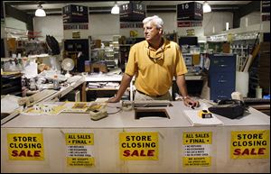 Surrounded by 'for sale' signs, Depot Building Supply co-owner Bryan Neal contemplates what he will do with the building and property after his store in Lexington, S.C., closes.