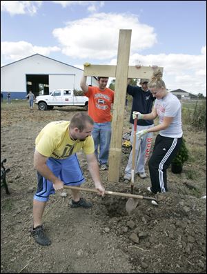 Bowling Green State University students, from left, Alex Binger, Tyler Strittmatter, Mike Krafft, and Anne Yenrick set up a cross at Serenity Farm near Luckey.