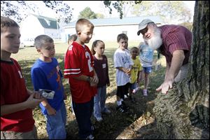 Dennis Walsh, a naturalist volunteer, describes to students from Oakdale School the characteristics of one of the trees at the Blue Creek Conservation Area.