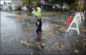 Mike Kurfess of Bowling Green's wastewater collection unit opens a drain on West Wooster Street after the storm passed. Meteorologists said it was notable for the low pressure at its center.