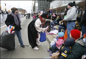 Distinguished Clown Corps member Nancy Rodgers of Perrysburg makes an animal balloon for a parade-goer while her daughter, Ani Rodgers, left, helps carry the bag of balloons.