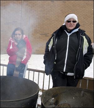 Melissa Haas, 16, a junior, left, and Interact Club adviser Sue Jones warm themselves in front of fire barrels. 