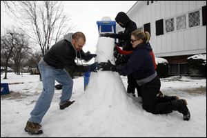 SLUG:  ROV snowarch                         12/25/2010 The Blade/Amy E. Voigt                         Sylvania, Ohio   CAPTION:  Darrell Breese, left, Cari Rand, center, and Lindsay Latimer, right, pack down snow to make a life size snow arch with family on Christmas afternoon in Sylvania on December 25, 2010.