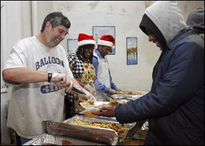 Paul Geller serves George Love at Thomas Temple Church of God. The free meal, the seventh annually, included baked turkey, baked ham, stuffing, macaroni and cheese, and mustard and turnip greens. 