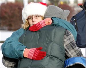 Cindy Nearhood gives a hug, which were distributed in abundance along with the razors, toys, food, and clothing outside the Main Library. Another volunteer, Jennifer Black, wore a 'Free Hugs' apron as she passed out dozens of banana-and-chocolate-chip muffins.