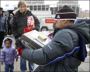 Chrystina Brake watches her son 9-year-old son Isaiah carry a large present as his 2-year-old sister Alisha stands by. Ms. Brake, who said she's unemployed and raising three children on her own, found a coat at the Christmas Day event for her 8-year-old daughter, Miah.