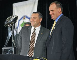 Mississippi State coach Dan Mullen, left, and UM coach Rich Rodriquez get a look at the Gator Bowl trophy to be awarded to Saturday's winner.