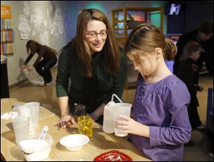 Patti DeBlasis, left, watches as her daughter Zoe DeBlasis, of Portland, Ore., makes snow at the Imagination Station without getting chilled. This snow is made from a super-absorbent polymer.