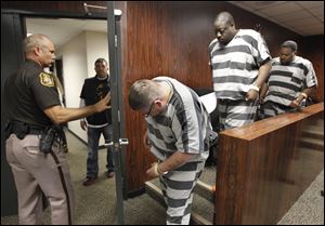 Martin Anderson of Indianapolis, left, Jimmy Laster of Ypsilanti, Michigan, and Charles Applewhite of the Detroit area, leave 1st District Court in Monroe, Michigan, after arraignments on dogfighting charges, Tuesday.