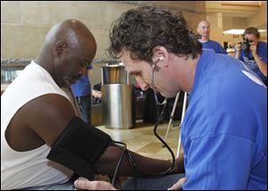 Mike Bell, mayor of Toledo and former fire chief, has his blood pressure checked at Franklin Park by Todd Arndt, a former firefighter.