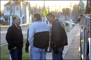 Sandusky police officers gather at the scene where fellow officer Andrew Dunn, 30, was shot and killed while stopping a bicyclist from Sandusky who was known to police. Evidence collected at the scene included a firearm and multiple shell casings.