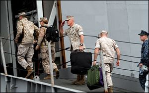 Sailors and Marines board the USS Bataan before the ship leaves the pier at Naval Station Norfolk, Wednesday in Norfolk, Va. The USS Bataan Amphibious Ready Group is deploying to the Mediterranean Sea to aid international efforts in Libya.