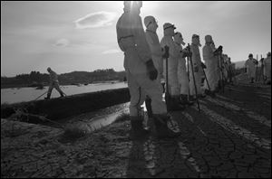 Japanese police wearing protective radiation suits search for the bodies of victims of the tsunami in the Odaka area of Minamisoma, inside the deserted evacuation zone established for the 20 kilometer radius around the Fukushima Daiichi nuclear reactors.