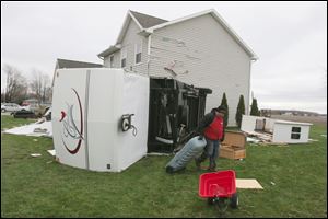 Jim Furman salvages what he can from a wind-destroyed travel trailer outside a house on Grisell Road in Oregon. On the same road, a storage building struck a house. 