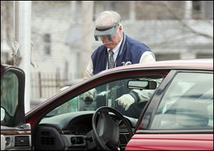 Toledo Police Department Det. William Goetz looks over the car that  a shooting victim.