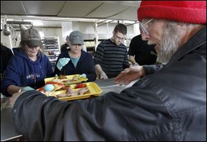 Volunteers Sally Royston, Debbie Trzaskowski, and Kevin Johnson, from left, serve an Easter meal to Jeff Laipply at the Madison Food Service and Community Center. This was the first time that Cherry Street Mission Ministries had surveyed guests for menu items.