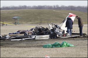 Investigators examine the wreckage of the plane that crashed at Munson Park in Monroe. The crash killed all three men aboard.