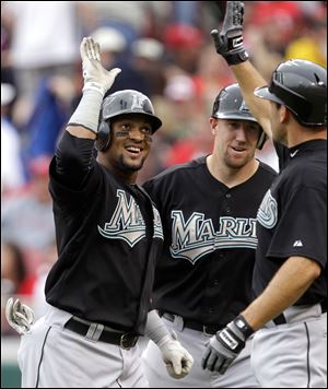 Florida Marlins' Emilio Bonifacio, left, is congratulated by teammates John Buck, center, and Greg Dobbs after hitting a three-run home run off Cincinnati Reds relief pitcher Nick Masset in the eighth inning of a baseball game Sunday in Cincinnati. Florida won 9-5.