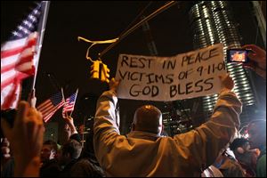 Herman Maisonave, of the Queens borough of New York, right, holds up a sign as he joins those gathered at ground zero in New York as they react to the news of Osama Bin Laden's death early Monday morning.