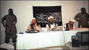 Exiled al-Qaida leader Osama bin Laden, center, is flanked by his aides and armed bodyguards in a 1998 meeting at an undisclosed location in Afghanistan, according to the source. In the background is a banner with a verse from the Quran, Islam's holy book. 