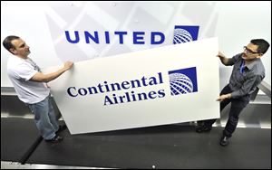 Rich Accordino, left, and Juan Perez-Wheeler remove an old Continental Airlines sign to reveal the new United Airlines logo featuring Continental's globe.