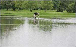 Mat Hudson of Point Place works on clearing a drain on the flooded 12 hole of the Toledo Country Club in South Toledo.