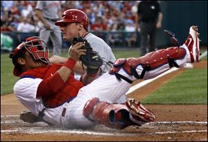 Philadelphia catcher Carlos Ruiz, left, tumbles after tagging out Cincinnati'S Jay Bruce at home plate after Bruce tried to score on a fielder's choice by Edgar Renteria in the second inning of a baseball game Wednesday.