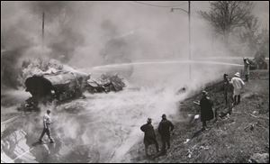 Firefighters from the Toledo Fire Department stand along the side of the Anthony Wayne Trail to fight the blaze. In all, 57 firefighters responded. The truck, driven by Edward Baum, 49, of Swanton, was mangled. Part of it overturned and part of it stayed on its wheels. 