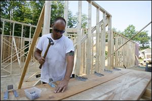 Jeff Shephard, owner of Jeff Shephard Construction, puts hangers on a ceiling beam while working on a home in the Shadow Woods subdivision