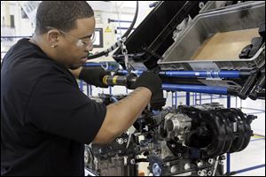 Larry Patterson, of Ypsilanti, attaches the wiring block to the rear of an engine at Chrysler's Dundee plant.