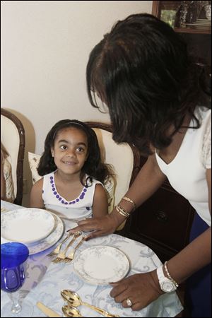 Taylor Halsey, 8, of Springfield Township, learns the role of each fork at a dinner setting with instructor Denise Cardwell.