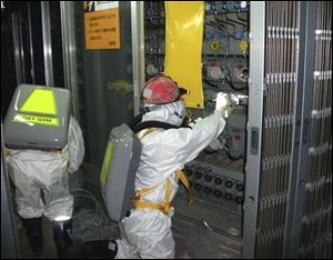 In this May photo released by Tokyo Electric Power Co., workers check the status of the water level indicator at the Unit 1 reactor building at the Fukushima Dai-ichi nuclear power plant.