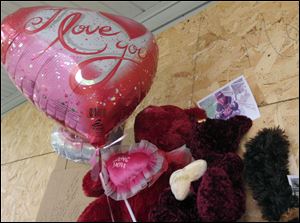 Balloons and stuffed animals have been attached to the boards covering the windows of the house on Grand Avenue where Montelle Taylor lived. The area is filled with gang activity, neighbors said.