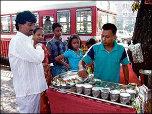 A street vendor in Mumbai makes paan, a South Asian chewing tobacco product made from the leaf of the Betel tree packed with a lime paste and spices, decorated with coconut shavings and cherries on top.