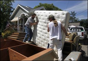 Mike Mertz, left, and Chris Delker load a mattress onto a trailer as they help Chris' father evacuate his Minot, N.D., home Thursday.