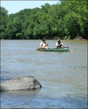 Matt Horvat dusts off his hat while on a bankside break during Tuesday's nearly 32-mile paddle down the Maumee River.