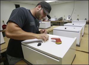 Daniel Cassavar applies insignias to breaker boxes as Netronex Energy Systems in Millbury. The company plans to move to the UT campus this month to be closer to other alternative energy firms. 