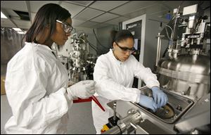 Magic Morehead, left, and Kendra Payton, Woodward High School seniors participating in a UT science and engineering program, load glass samples at the Wright Center for Photovoltaics.