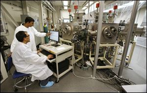 Deepak Sainju, left, and Puruswottam Aryal, UT doctoral students, monitor a solar-panel substrate process at a UT lab.