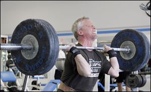 Weightlifter Jerry Huth, 56, is midway through the clean-and-jerk maneuver and will complete the lift by thrusting the 210 pounds of weight directly over his head with his arms fully extended.