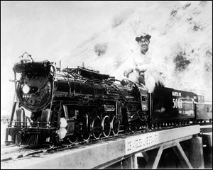 Mr. Mann sits atop the scale model train he built.