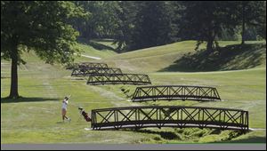 A golfer hits a shot near the bridges over the Inverness burn, a creek which slices through the property and comes into play on eight holes.