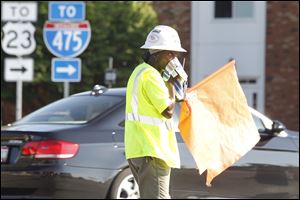 Mel Smith-Agin, a Miller Bros. Construction Inc. employee out of Archbold, wipes the sweat off of her face Thursday while directing traffic and construction vehicles at the corner of Briarfield Boulevard and Salisbury Road.