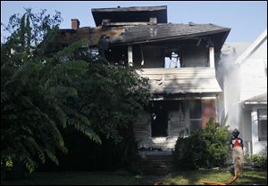 A firefighter sprays water on 656 Forsythe St. which caught of fire Thursday morning.