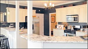 The kitchen’s antiqued white cabinets and dark walls make a perfect backdrop for the beautifully
veined granite countertop.